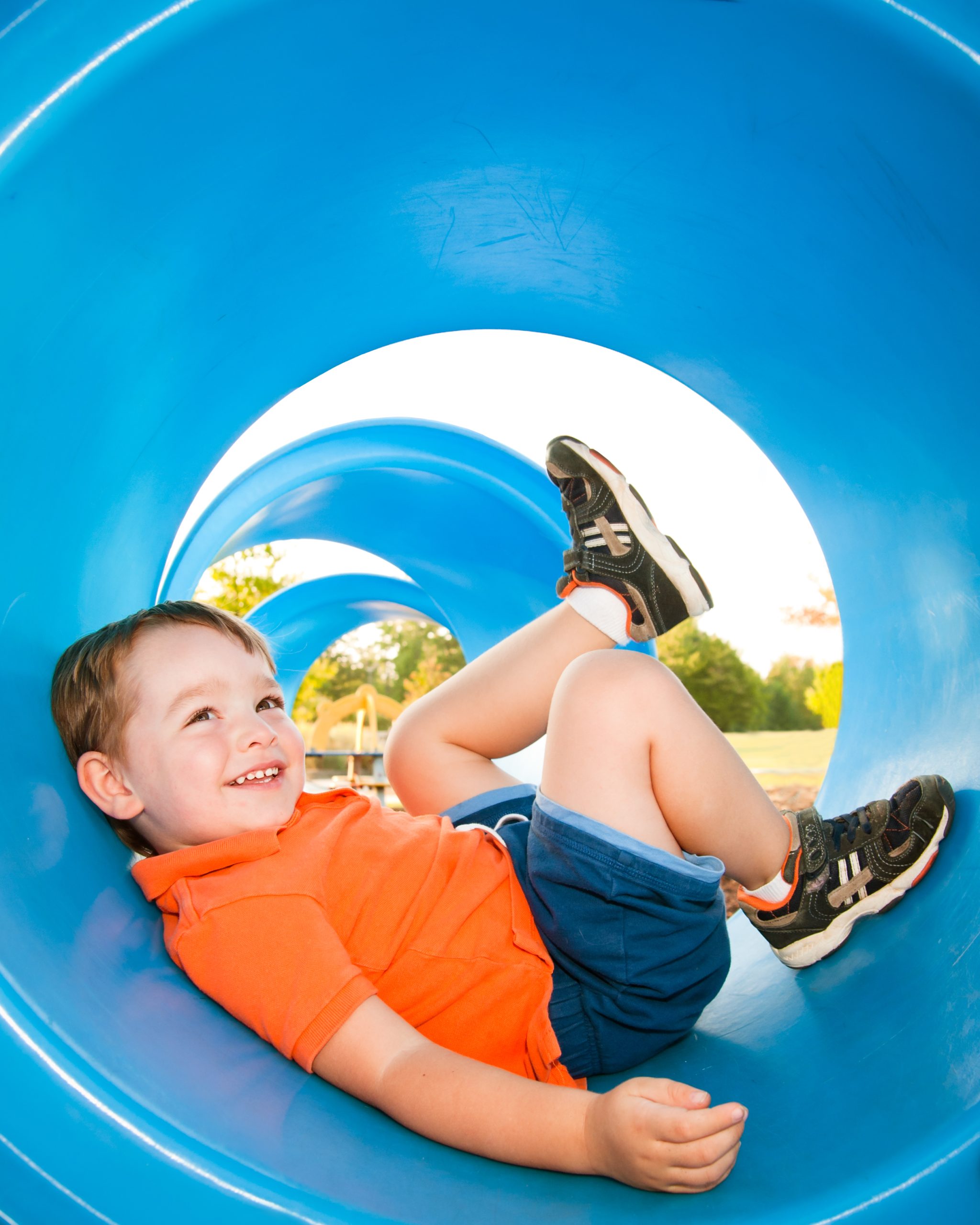 A child in a playground tunnel in a composite play structure